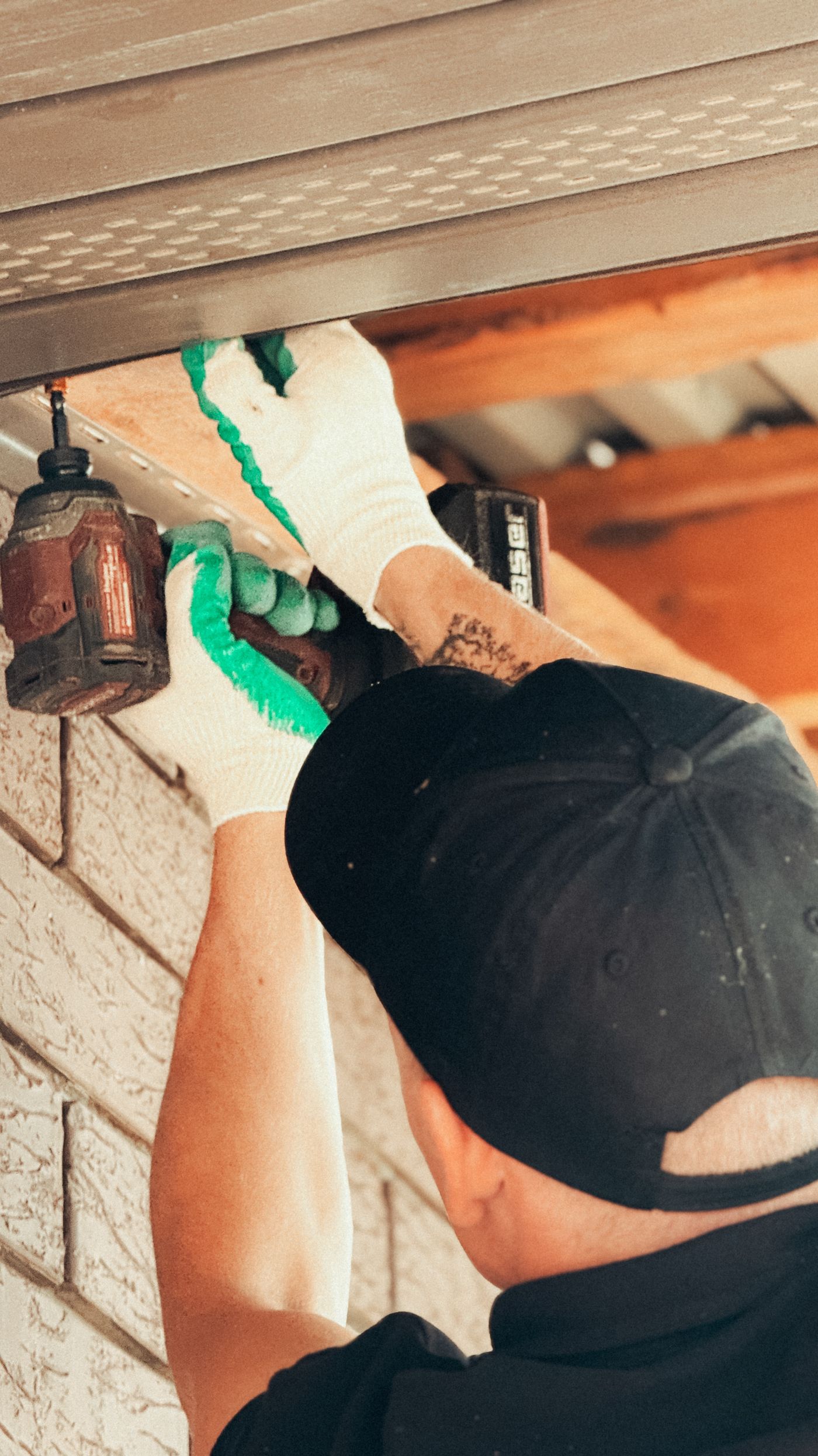 A technician on a ladder installing a security camera outdoors