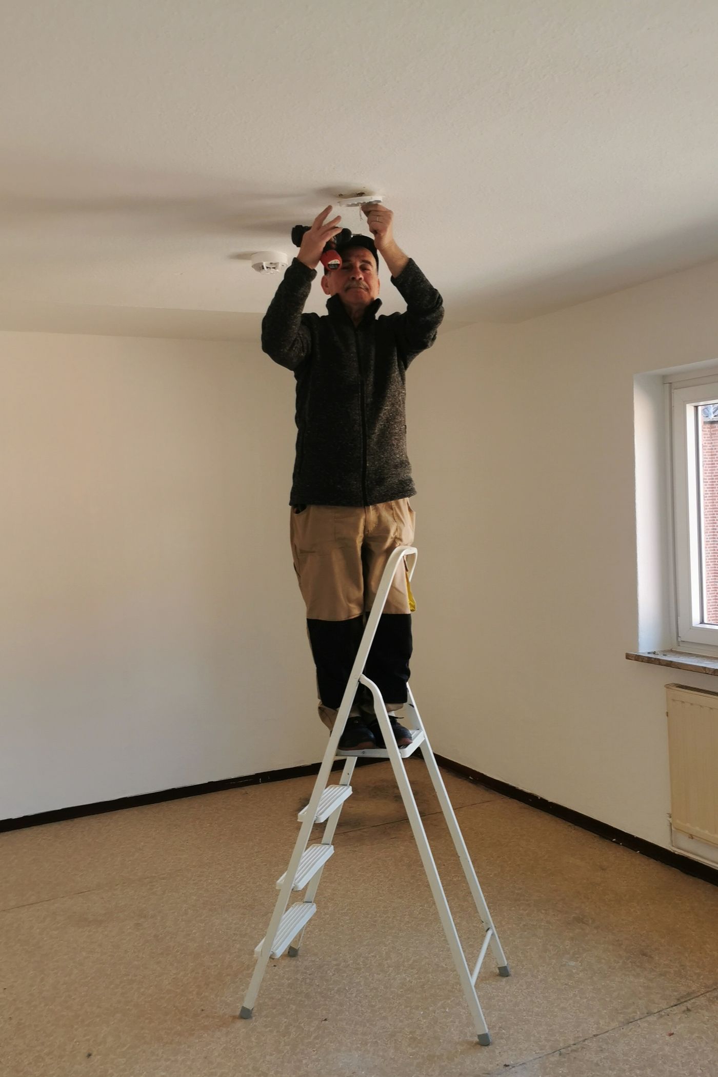 A Drishti technician on a ladder fixing a ceiling fixture